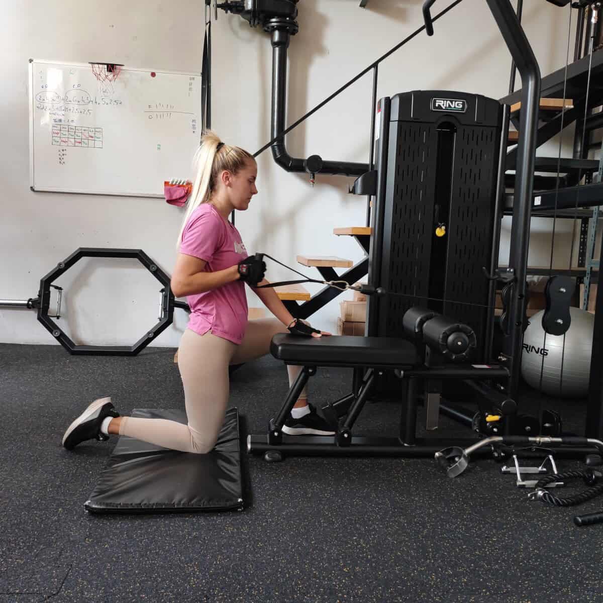 Vežbačica radi vežbu na kablu u studiju Workout Team